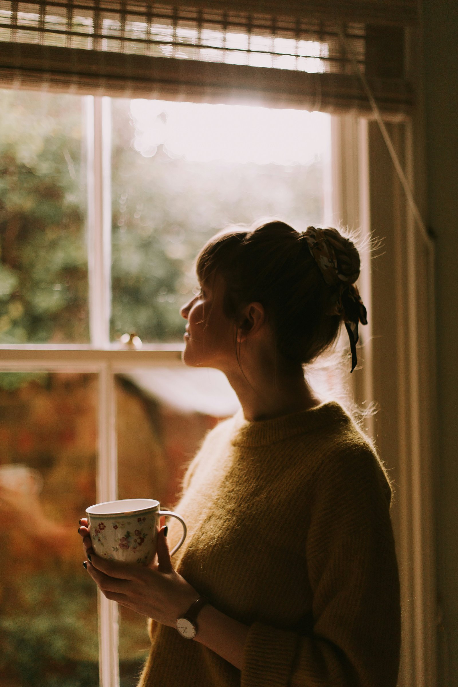 Woman having her morning coffee by the window
